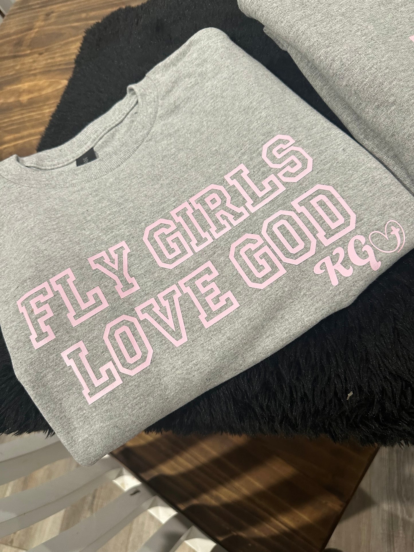 Gray sweatshirt with pink text on a wooden surface